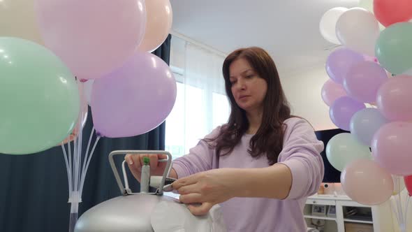 Woman Using Helium Tank Blowing Up Balloons to Decorate Home for Party Colorful Balloons for