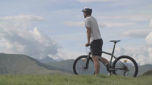 Young Athletic Man in Summer Day is Enjoying the Panorama Outdoor on Mountain After Went for a Ride