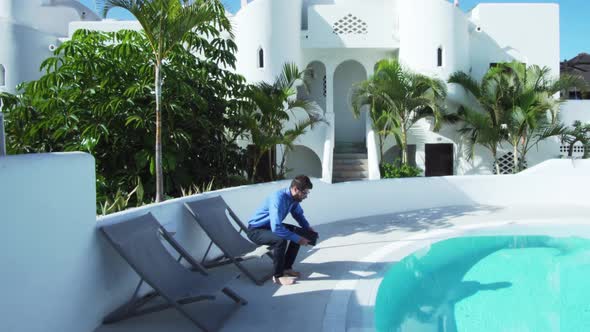 Young businessman is walking and working on tablet near the pool in warm country.