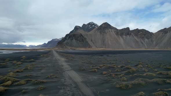 Iceland Drone of Vestrahorn Stoksness Black Sand Beach with long lonely Dirt Road