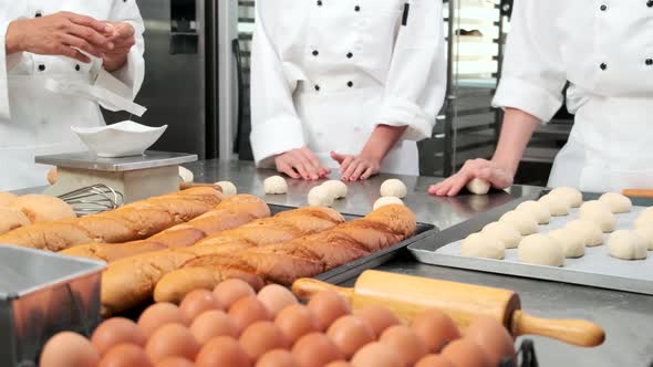 Chefs are preparing pastry dough, baking bakery food on a stainless steel table.