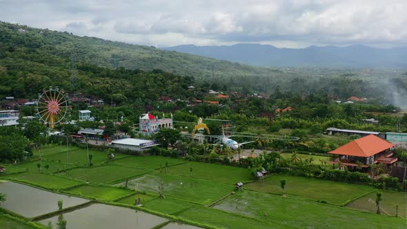 amusement park in mountain field of bali with airplane and ferris wheel, aerial