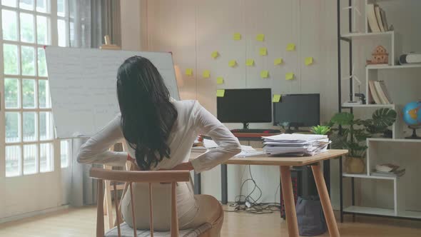 Back View Of Asian Woman Having Backache While Working Hard With Documents At The Office