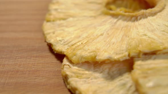 Dried pineapple ring close up. Textured fibrous surface of a dry dehydrated fruit on a board