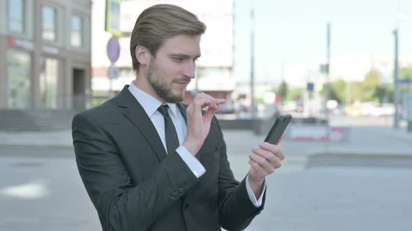 Businessman Celebrating Online Success on Smartphone Outdoor