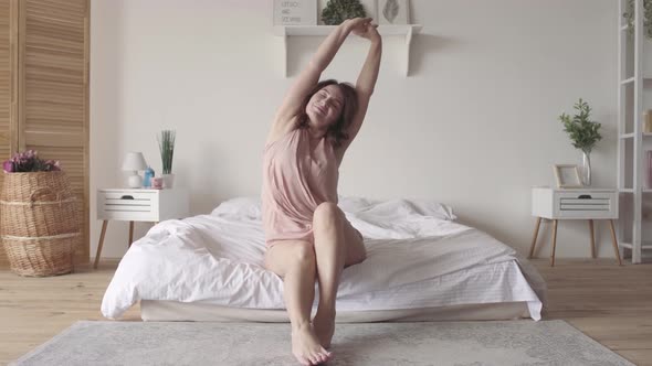 Pretty Mature Brunette Slowly Stretches Sitting on the Bed in the Morning