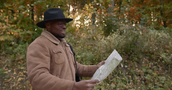 Young Black Traveler with a Map Walking in Forest