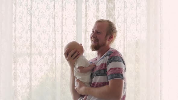 Bearded Young Father Gently Hugs and Rocking a Newborn Sleeping Baby in His Arms at Home. Gental
