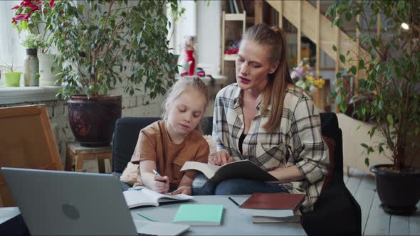 The Girl Reads the Text From a Laptop and Writes in a Notebook