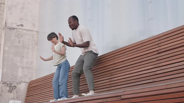 Diverse Couple Dancing on Bench Outdoors