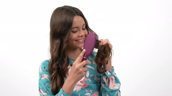 Cheerful Teen Girl Comb Long Healthy Wavy Hair with Hairbrush Showing Their Strength Hair Care