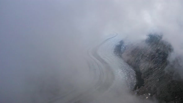 Aerial reveals view of Aletsch glacier covered in Fog, Switzerland