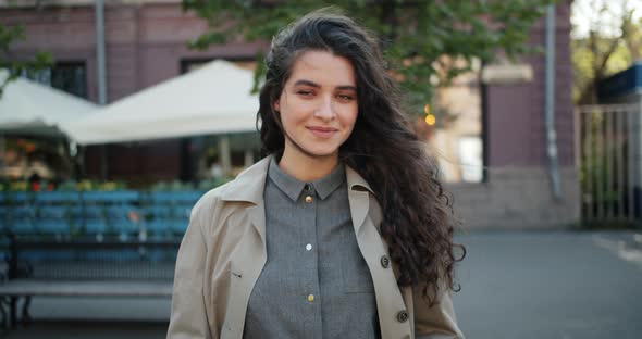 Portrait of Pretty Young Woman Standing Outdoors in the Street Smiling