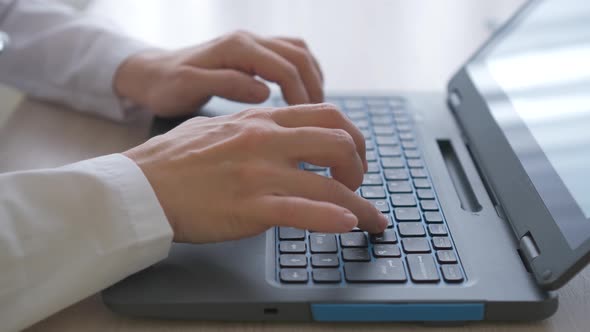 Girl's hands typing on a laptop on the table close-up