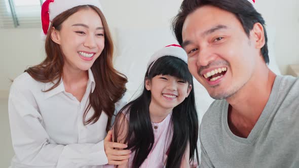 Asian loving Parents using mobile phone with little kid daughter video call online with family.