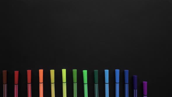 School Markers of Different Colors Are Located on the Black Surface. Stop Motion Animation