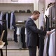 A Side View Slow Motion Shooting of a Man in a Clothing Boutique Standing Near the Clothes Hanger - VideoHive Item for Sale