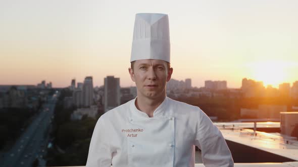 Portrait of a professional chef: he looks into the camera while having a barbecue on the roof