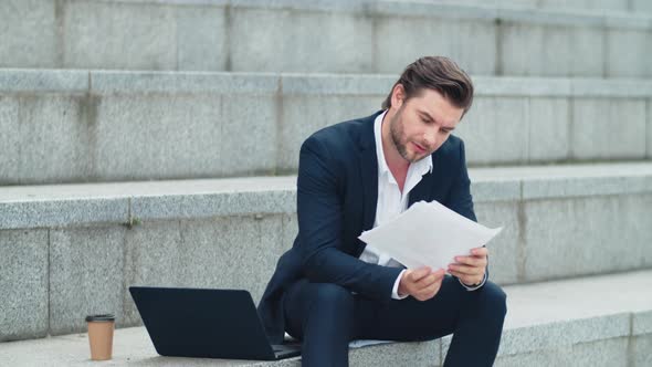 Businessman Reading Business Papers Outdoors. Male Manager Celebrating Victory