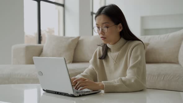 An Asian Woman with Glasses Uses a Laptop Rejoices at the Victory Feels Excitement Got the