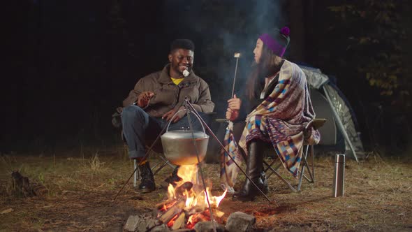 Tourists Couple Eating Marshmallows By Campfire