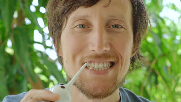 A Young Man Uses a Portable Water Flosser Dental Oral Irrigator To Clean His Teeth