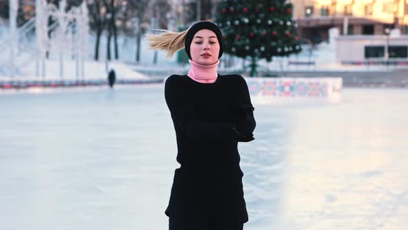 Young Woman Training Her Figure Skating on Public Ice Rink and Looking in the Camera