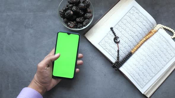 Using Smart Phone Holy Book Quran and Rosary on Table