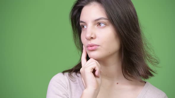 Young Beautiful Woman Thinking Against Green Background