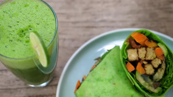 Top View of Healthy Vegan Lunch of Plant Base Green Wrap and Freshly Squeezed Vegetable Juice