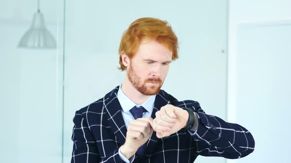 Redhead Businessman Using Smartwatch at Work in Office