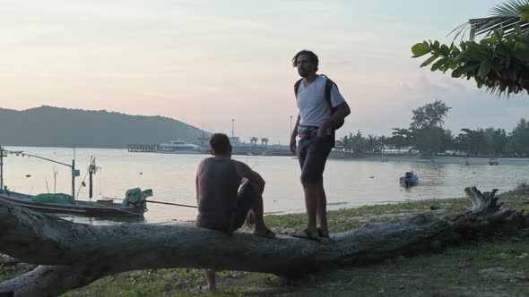 Silhouette of Men on the Background of the Sea in the Light of the Setting Sun