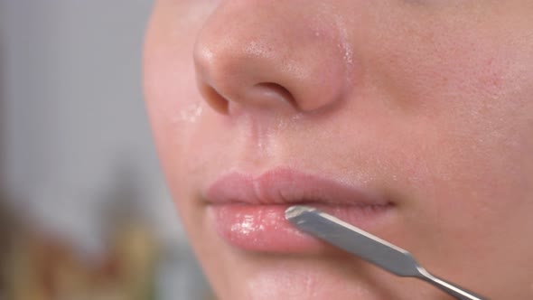 Preparing the Model's Skin for Applying Makeup. Lip Treatment with a Spatula and Lip Balm. Close Up.