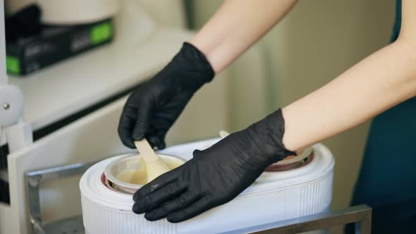 Master of Hair Removal Prepares Wax for Depilation Using Wooden Spatula