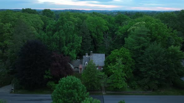 Aerial of large countryside estate. Private mansion surrounded by trees. Beautiful shot at sunrise.