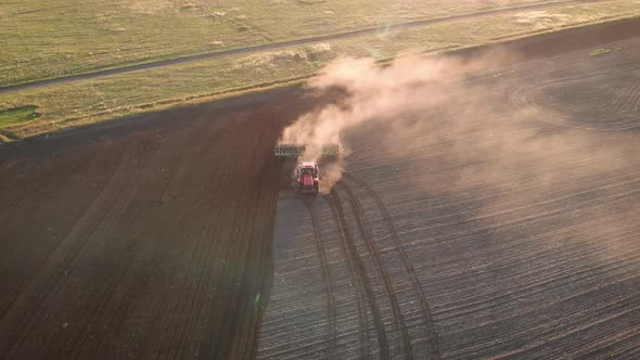 Aerial View Modern Red Tractor on the Agricultural Field on Sunset Time. Tractor Plowing Land