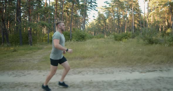 Muscular Man in Sportswear Jogging at Forest