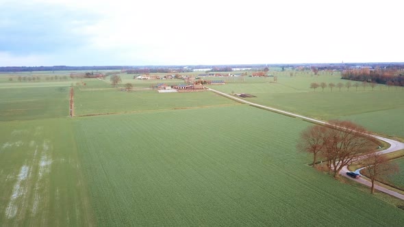 Aerial View of a Field with a Winding Asphalt Country Road Shot with a Drone