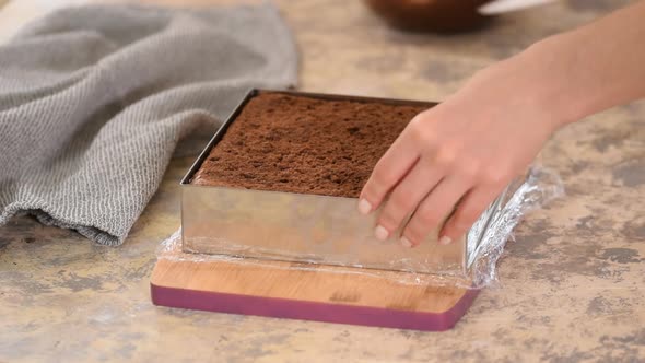 Hands Remove Metal Shape From a Chocolate Cake