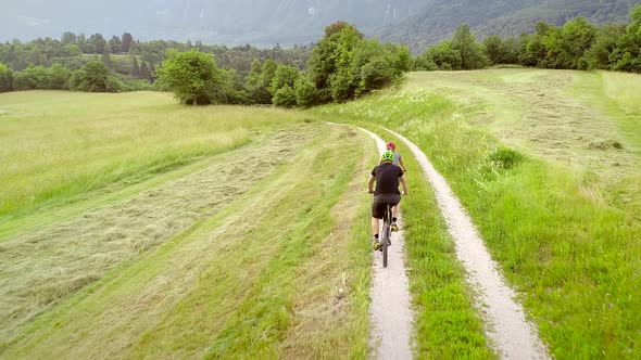 Aerial view of two cyclists riding bike in the forest on dirt road at Slovenia.