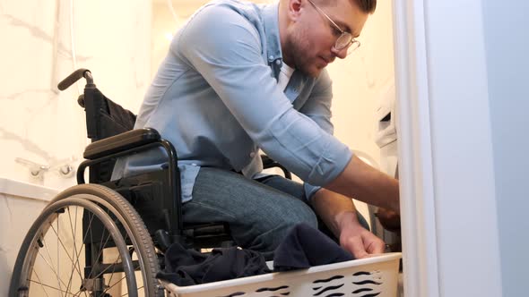 Impaired Man in Wheelchair Put Laundry in Washing Machine