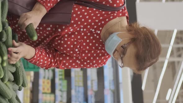 Senior Woman Choosing Cucumbers in Grocery