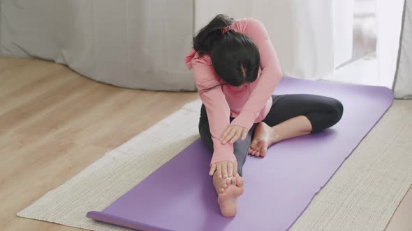 Beautiful Asian woman body flexibility stretching her leg and warm-up doing yoga.