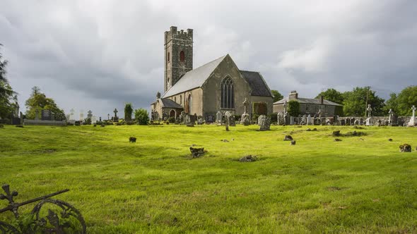 Time lapse of historical cemetery and medieval church in rural Ireland with passing clouds and sunsh