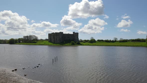 Drone flying over river with Carew Castle in background, Wales. Aerial forward