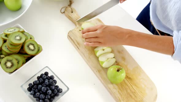 Woman cutting green apple on chopping board