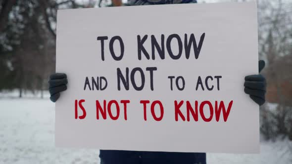 To Know and Not to Act is Not to Know is Written on a plackat. Single picket.