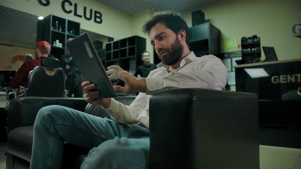 Young Bearded Caucasian Man Checking Socials on a Tablet PC