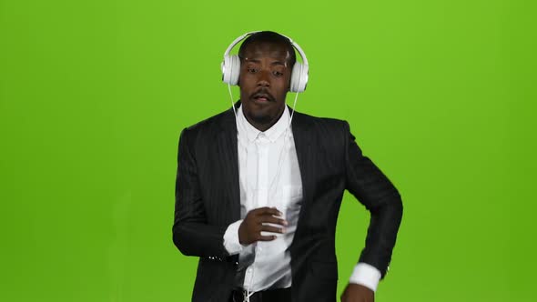 African American Man Dances Motion Latin and Listens To Music in the Earphones. Green Screen