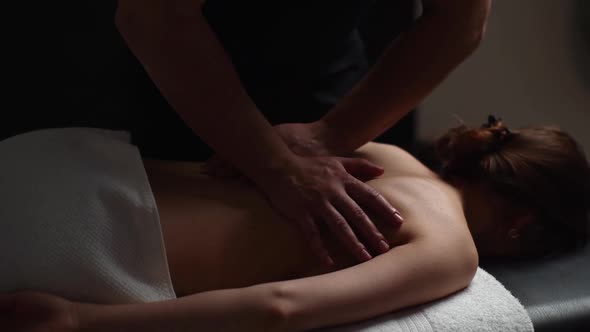 Closeup of Chiropractor Male Massaging Young Woman Lying on Massage Table Pushing on Spine